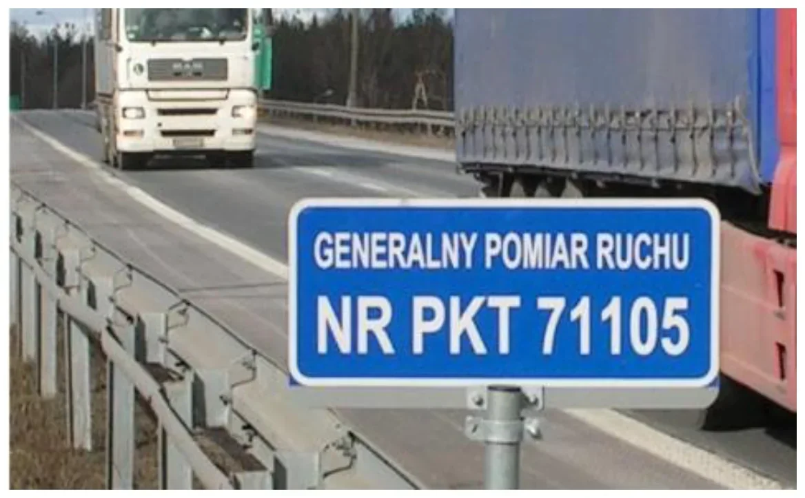 Zdjęcie niebieskiej tablicy GENERALNY POMIAR RUCHU NR PKT 71105 przy barierze drogowej