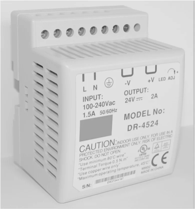 Zdjęcie urządzenia DR-4524 na szynę z zaciskami i tabliczką INPUT 100-240 Vac, OUTPUT 24 V 2 A