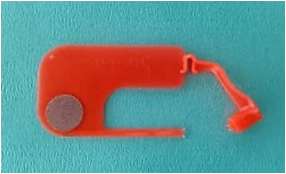 Czerwony plastikowy element z okrągłym polem wskaźnika na niebieskim tle