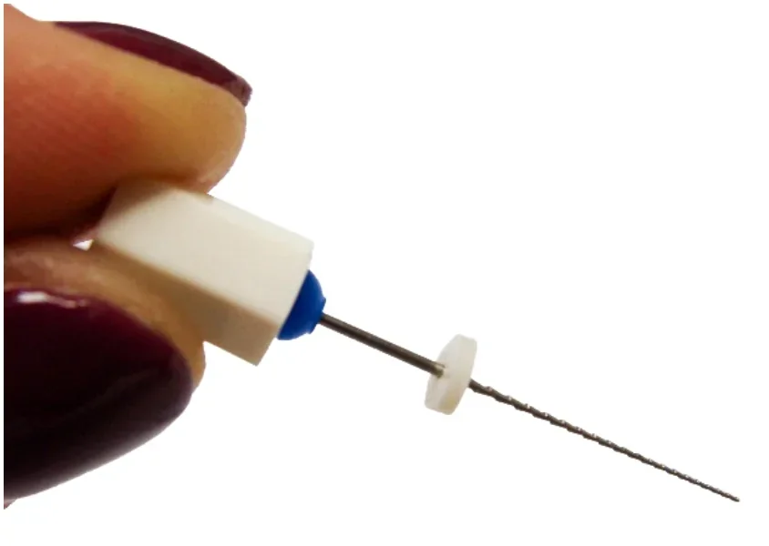 Instrument endodontyczny trzymany w palcach, z okrągłą podkładką na części pracującej